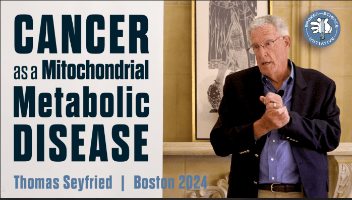 A speaker presenting on the topic 'Cancer as a Mitochondrial Metabolic Disease' in Boston 2024, with graphic text overlay and the Broken Science Initiative logo.